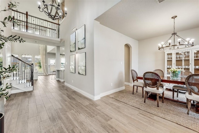 interior space with an inviting chandelier, light wood-style flooring, and arched walkways