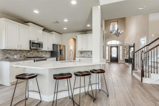 kitchen with a sink, white cabinetry, stainless steel appliances, and light countertops