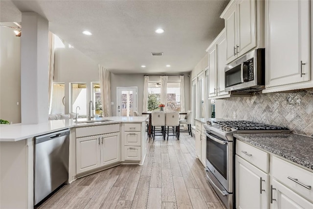 kitchen featuring stainless steel appliances, backsplash, a sink, and white cabinetry