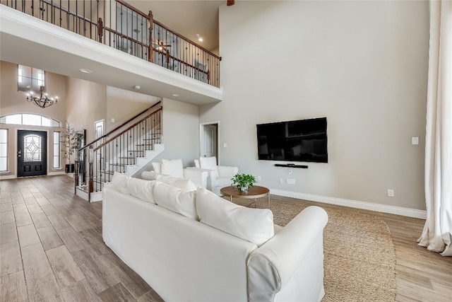 living room with an inviting chandelier, stairway, baseboards, and wood finished floors