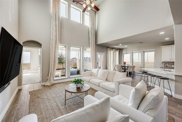 living room with baseboards, ceiling fan, light wood-style flooring, and a healthy amount of sunlight