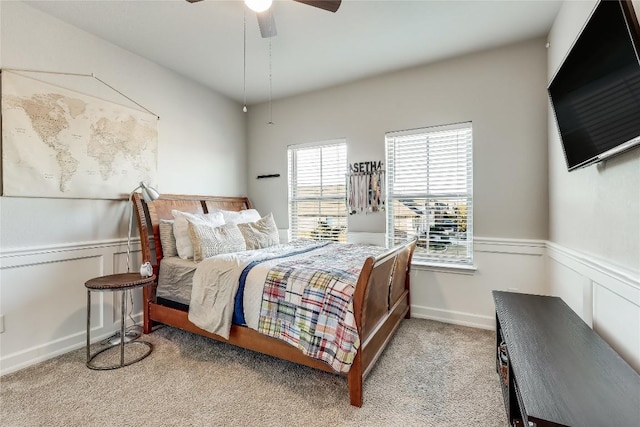 carpeted bedroom featuring ceiling fan and wainscoting