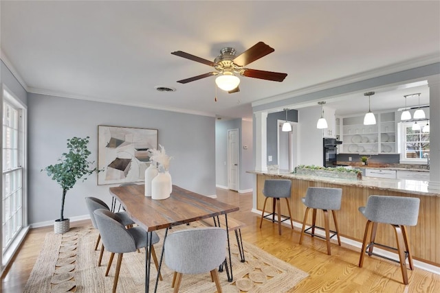 dining room featuring light wood-style floors, plenty of natural light, visible vents, and ornamental molding