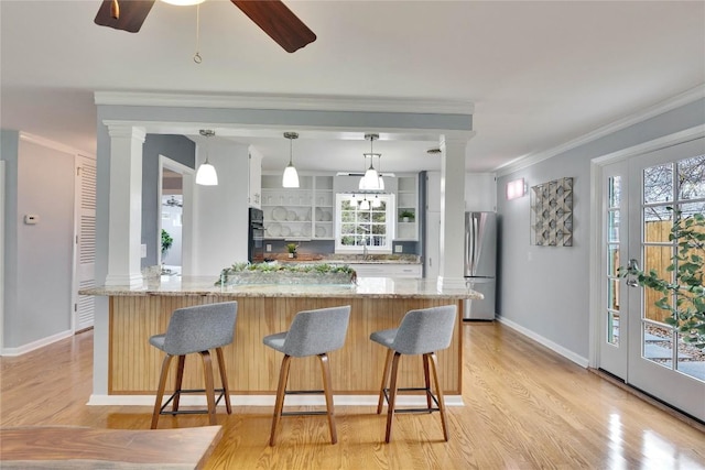 kitchen with a kitchen bar, hanging light fixtures, ornamental molding, freestanding refrigerator, and ornate columns