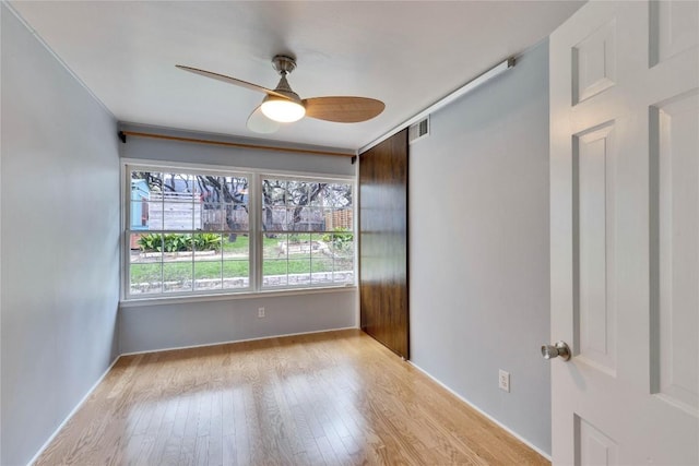 unfurnished room with light wood-type flooring, visible vents, and a ceiling fan