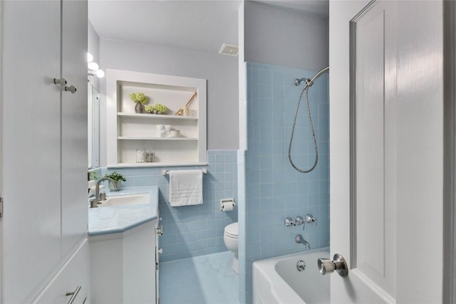 bathroom featuring built in shelves, tile walls, toilet, tub / shower combination, and vanity