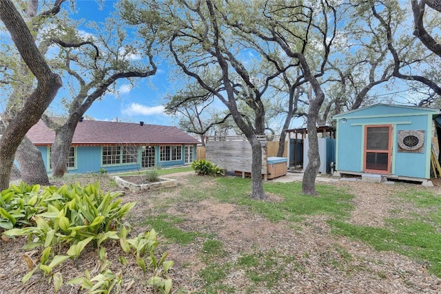 view of yard featuring a storage unit, an outdoor structure, fence, and a vegetable garden