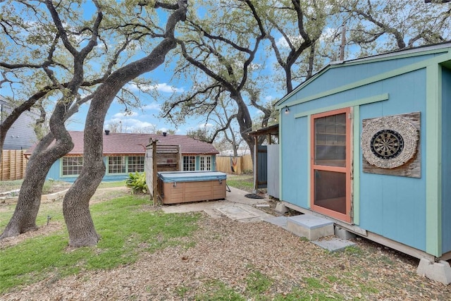 view of yard with a hot tub, fence, and an outdoor structure