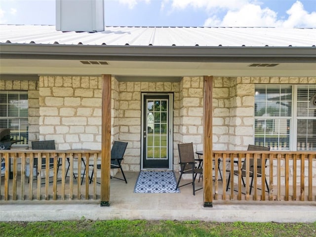 doorway to property with stone siding and covered porch