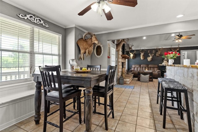 dining area with ceiling fan, wainscoting, crown molding, and light tile patterned floors