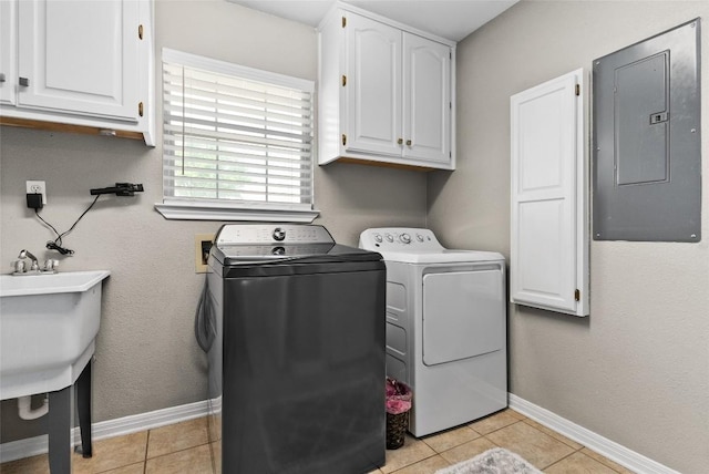 clothes washing area featuring light tile patterned floors, baseboards, cabinet space, electric panel, and washing machine and clothes dryer