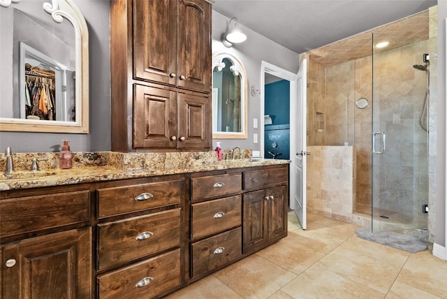 full bathroom featuring double vanity, a stall shower, a spacious closet, and a sink