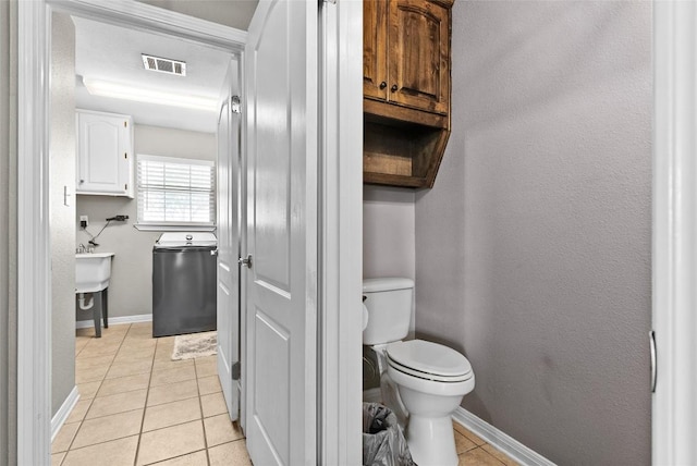 half bath with a textured wall, tile patterned flooring, toilet, visible vents, and baseboards