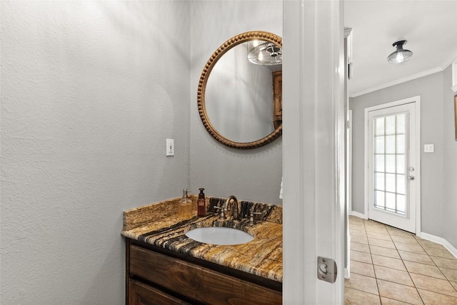 bathroom featuring baseboards, tile patterned floors, vanity, and crown molding