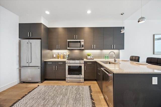 222 W Ave Unit 2403, Austin, TX 78701 - kitchen with stainless steel appliances, light wood-style floors, pendant lighting, decorative backsplash, and a peninsula