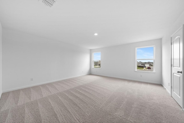 empty room featuring light colored carpet, visible vents, baseboards, and recessed lighting