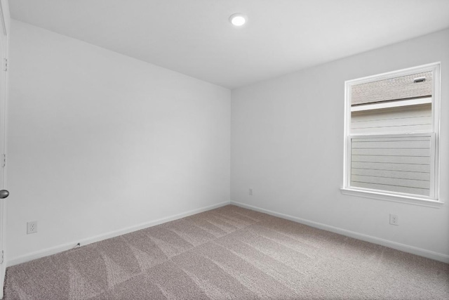 spare room featuring carpet flooring and baseboards