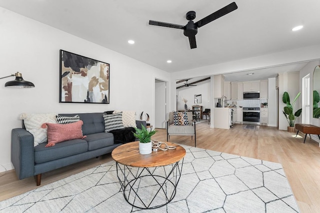 living room with light wood-style flooring, a ceiling fan, and recessed lighting