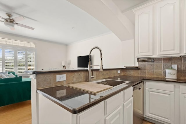 kitchen featuring decorative backsplash, white cabinetry, a sink, and stainless steel dishwasher