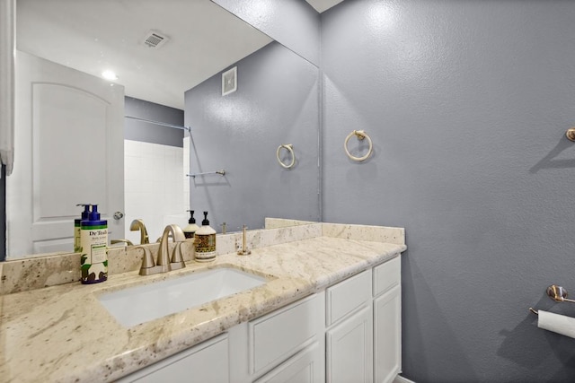 bathroom featuring visible vents, a textured wall, and vanity