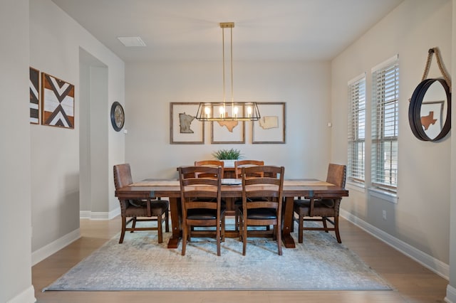 dining space featuring light wood finished floors, baseboards, and a notable chandelier