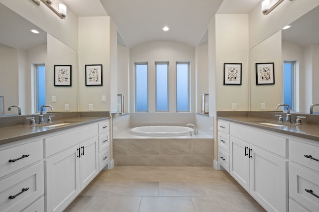 bathroom with lofted ceiling, two vanities, a sink, and a bath