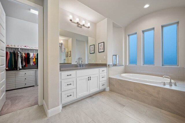 full bath featuring lofted ceiling, a spacious closet, vanity, tile patterned flooring, and a bath