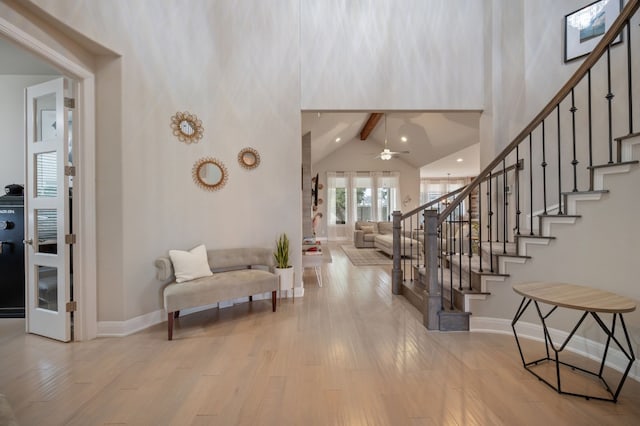 foyer featuring high vaulted ceiling, stairway, and light wood-style flooring