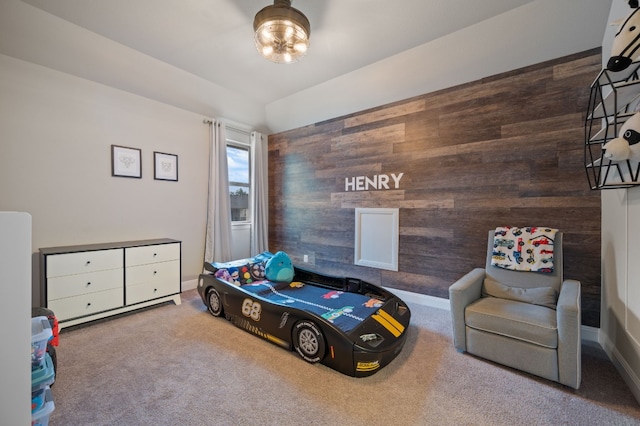 bedroom with carpet floors, an accent wall, wood walls, and baseboards