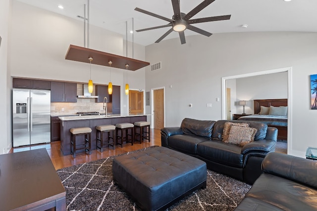 living area with ceiling fan, visible vents, vaulted ceiling, and dark wood-style flooring