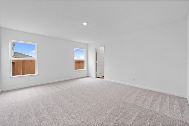 spare room featuring light carpet, baseboards, and recessed lighting