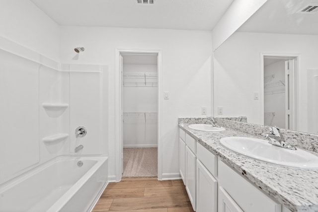 bathroom with shower / bathtub combination, visible vents, a sink, and wood finished floors