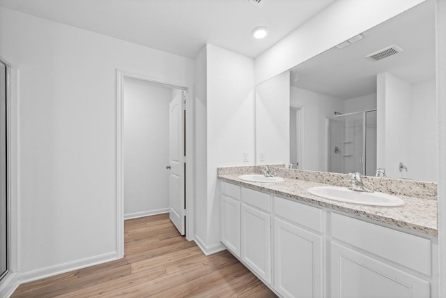 bathroom featuring a shower stall, visible vents, a sink, and wood finished floors