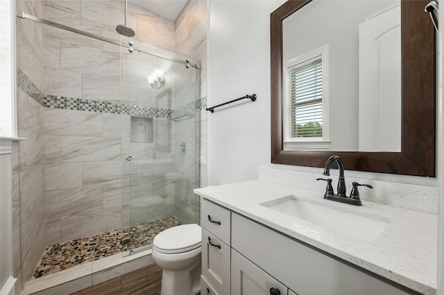 bathroom with a stall shower, vanity, and toilet