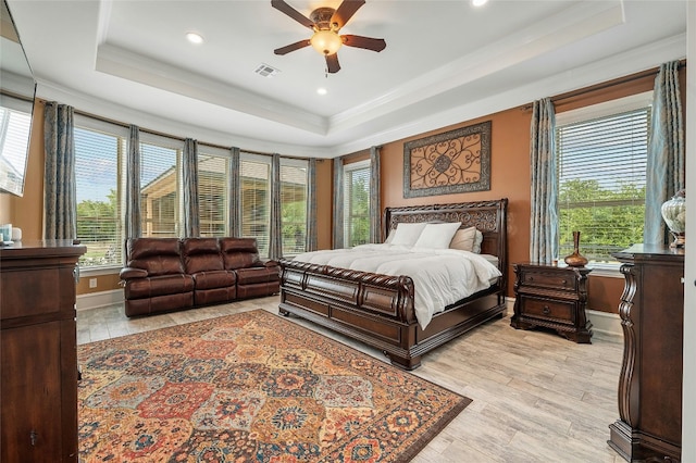 bedroom featuring light wood-type flooring, baseboards, visible vents, and a raised ceiling