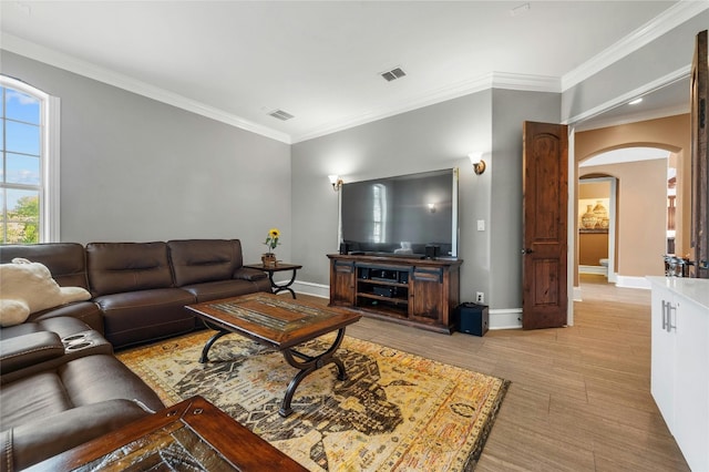 living room featuring arched walkways, crown molding, and baseboards