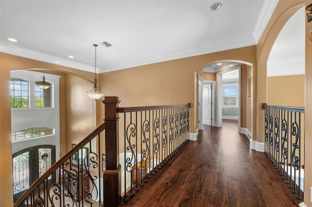 corridor with arched walkways, dark wood-style flooring, crown molding, and baseboards