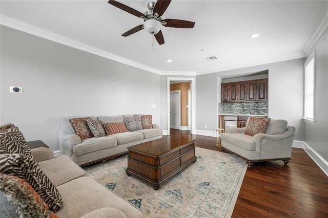 living room with crown molding, visible vents, a ceiling fan, wood finished floors, and baseboards