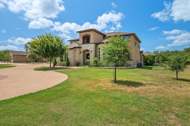 mediterranean / spanish-style home featuring stucco siding, central air condition unit, concrete driveway, a front yard, and stone siding