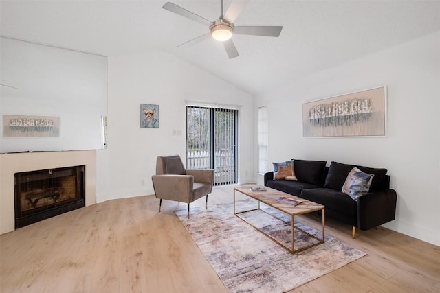 living area with ceiling fan, a fireplace, vaulted ceiling, and wood finished floors