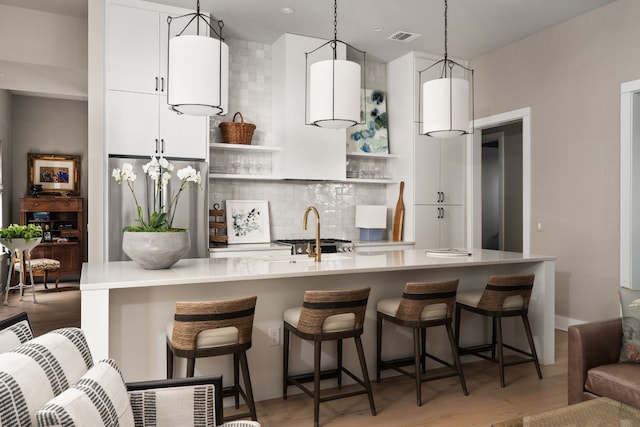 kitchen featuring tasteful backsplash, stainless steel refrigerator, hanging light fixtures, light countertops, and open shelves