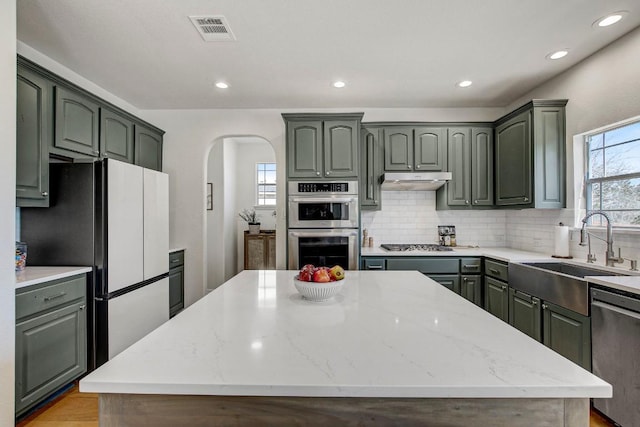 kitchen featuring a kitchen island, visible vents, stainless steel appliances, and a sink