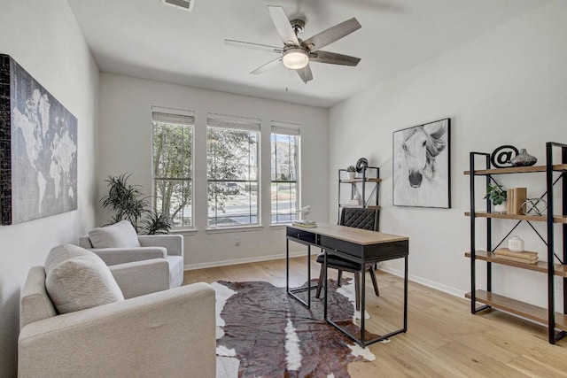 home office featuring light wood finished floors, ceiling fan, visible vents, and baseboards