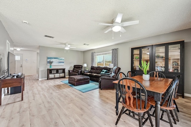 dining room featuring ceiling fan, a textured ceiling, visible vents, and light wood-style floors