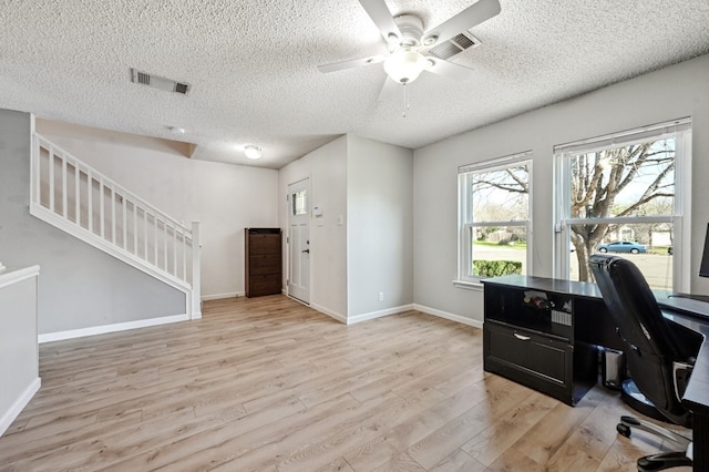 home office with light wood finished floors, baseboards, visible vents, and a ceiling fan