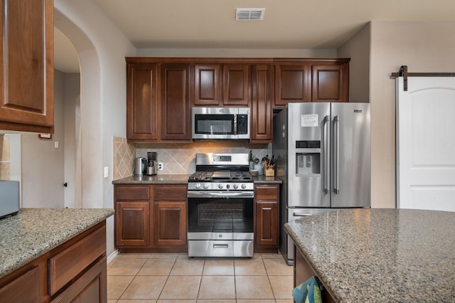 605 Hickory Run Dr, Cedar Park, TX 78613 - kitchen featuring stainless steel appliances, tasteful backsplash, arched walkways, and light stone countertops