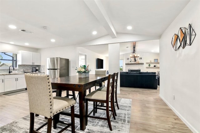 dining area with vaulted ceiling with beams, recessed lighting, light wood-style flooring, and an inviting chandelier