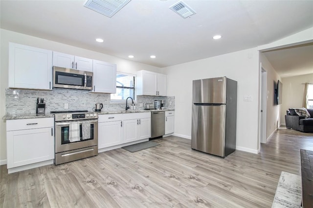 kitchen with light wood-style floors, appliances with stainless steel finishes, visible vents, and tasteful backsplash