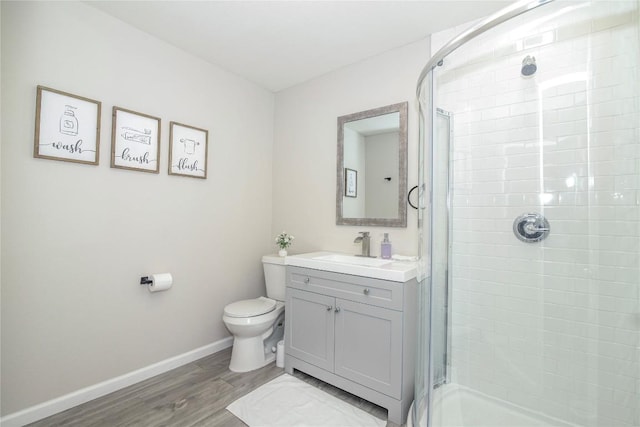full bath featuring vanity, wood finished floors, toilet, baseboards, and a stall shower