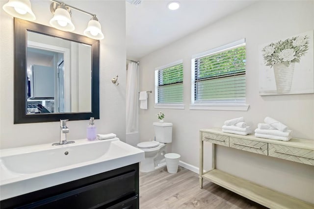 bathroom with vanity, curtained shower, wood finished floors, toilet, and baseboards